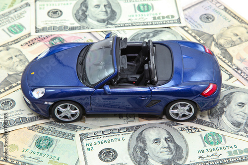 Sport car model on pile of US dollar banknotes