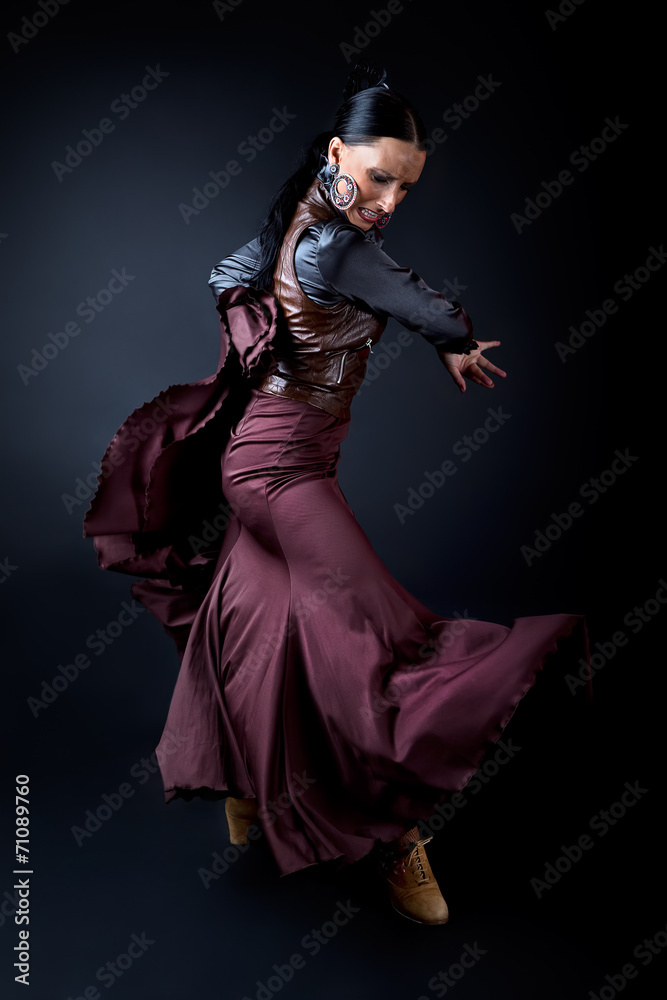 Young flamenco dancer in beautiful dress on black background.