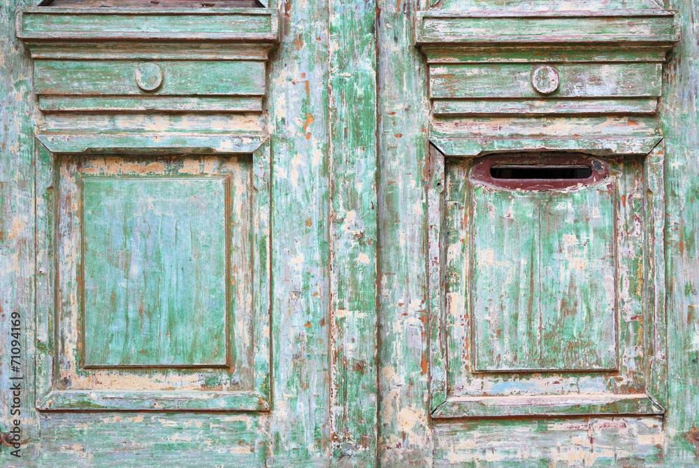 Old worn wooded door with green paint peeling off