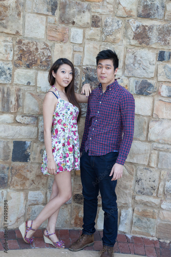 Romantic Asian couple outside by a stone wall