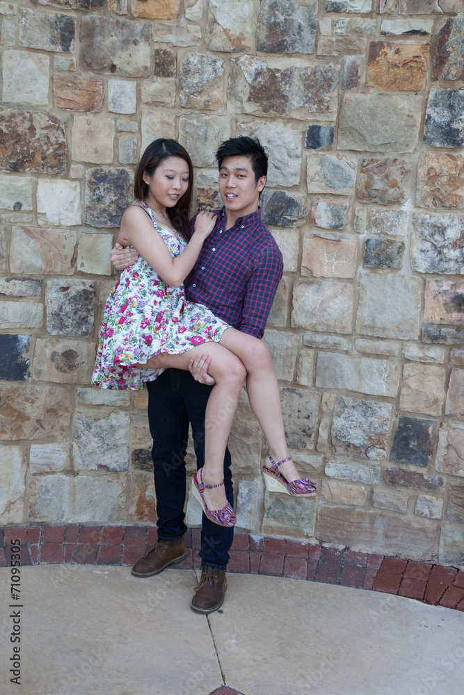 Romantic Asian couple outside by a stone wall