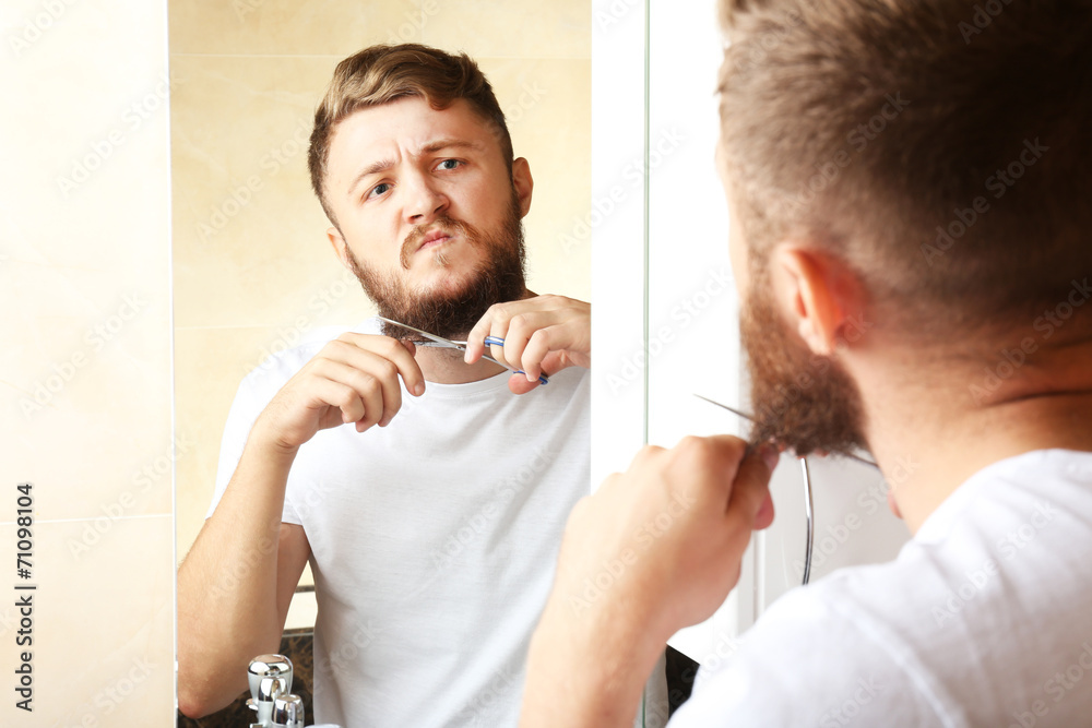 Obraz premium Young man shaving his beard in bathroom