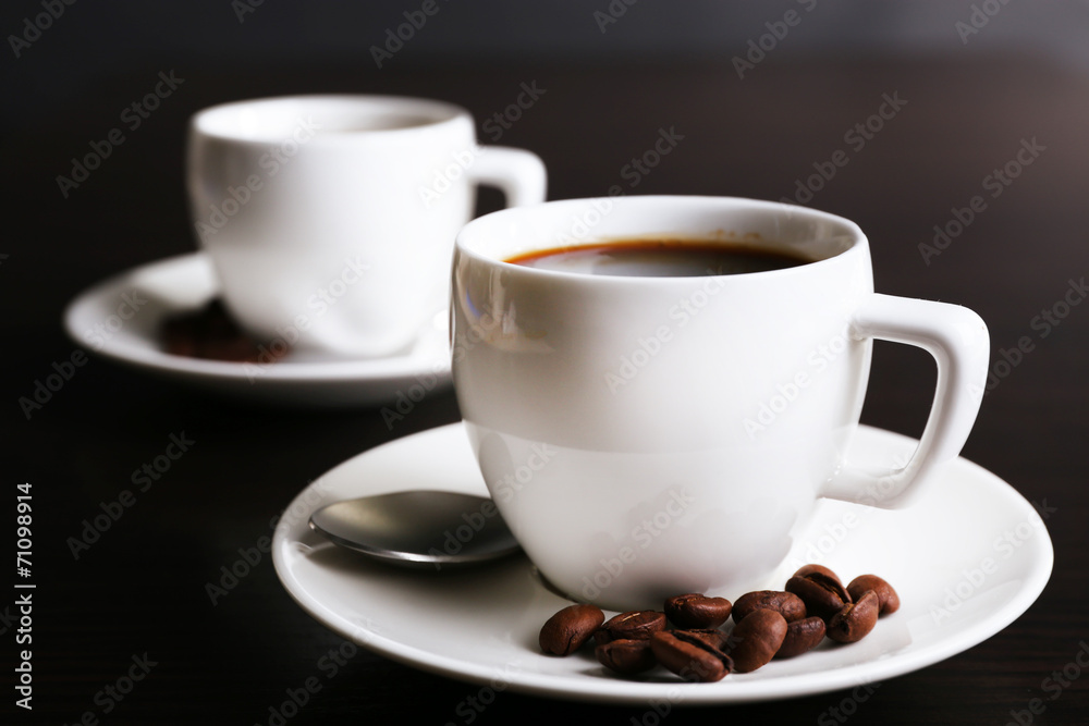 Two cups of coffee and coffee beans on dark background Two cups of coffee and coffee beans on dark background