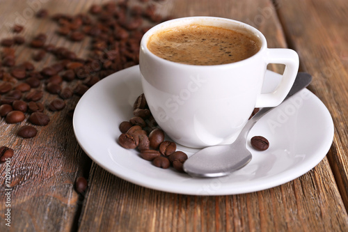 Cup of coffee with milk and coffee beans on wooden background