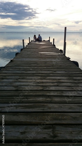 Pareja de novios sentados en muelle