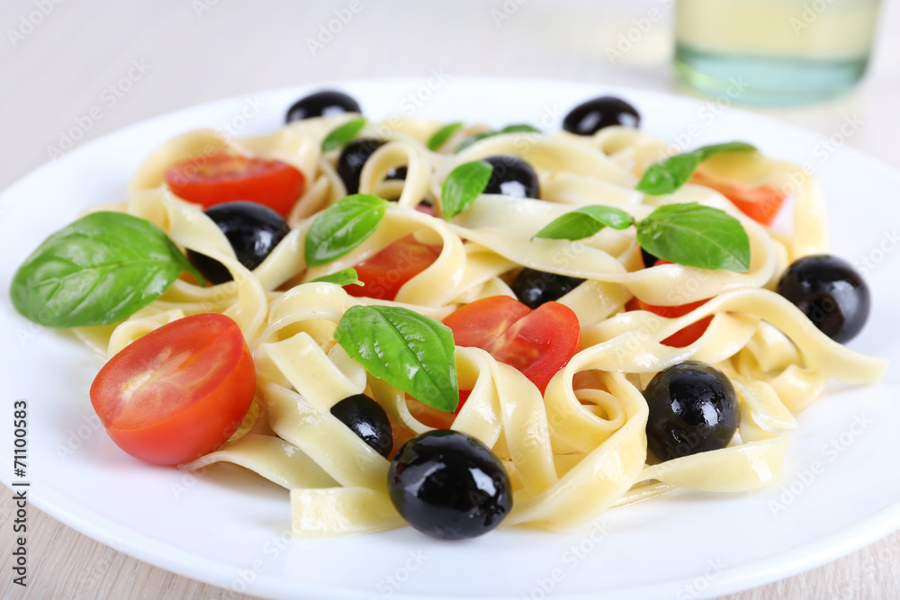 Spaghetti with tomatoes, olives and basil leaves