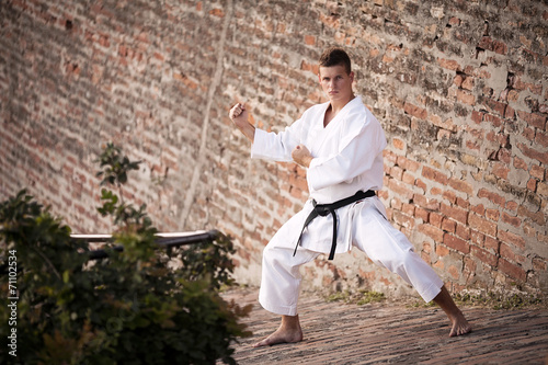 Young man practicing martial arts in front of a brick wall © bokan