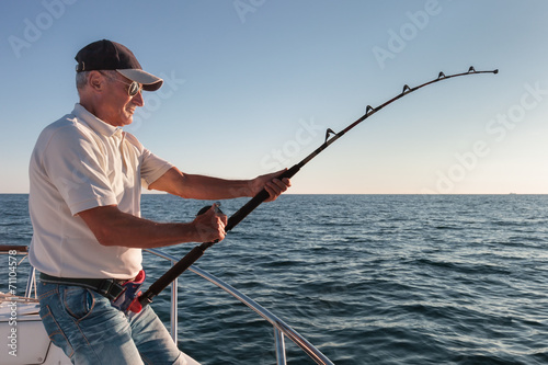 Fototapet fisherman fishing from the boat
