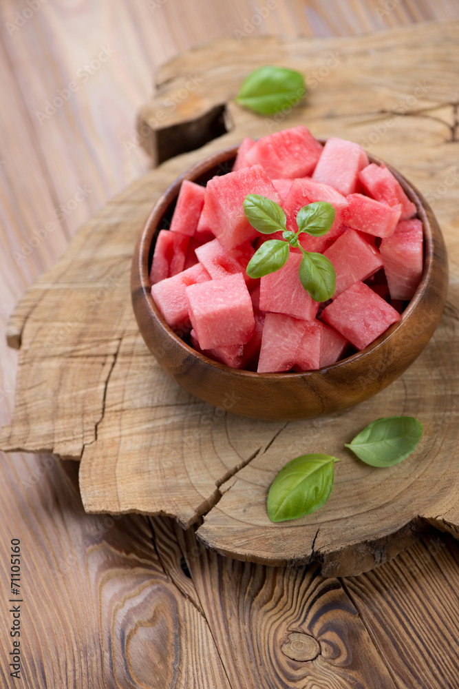 Wooden bowl with watermelon cubes and basil, high angle view Wooden bowl with watermelon cubes and basil, high angle view