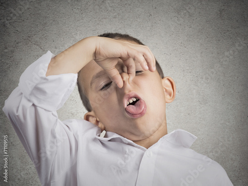 boy with disgust on face pinches nose something stinks