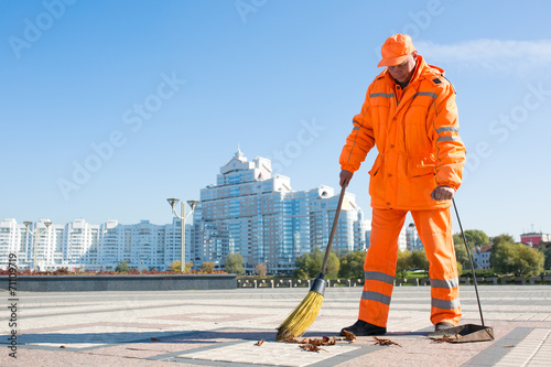 Man road sweeper caretaker cleaning city street with broom tool photo