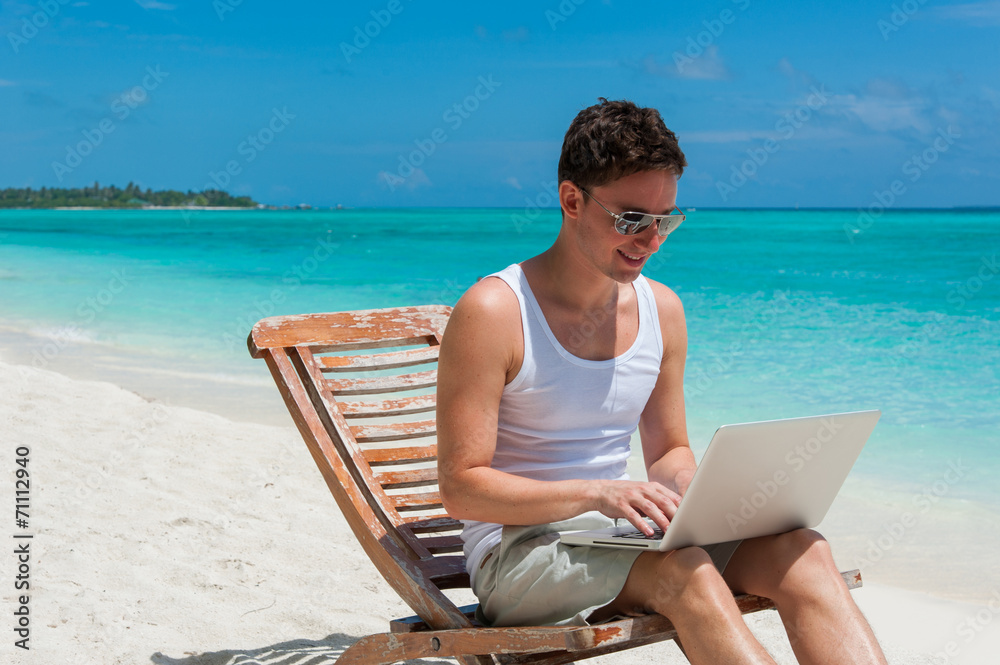 Man relaxing at the beach with laptop