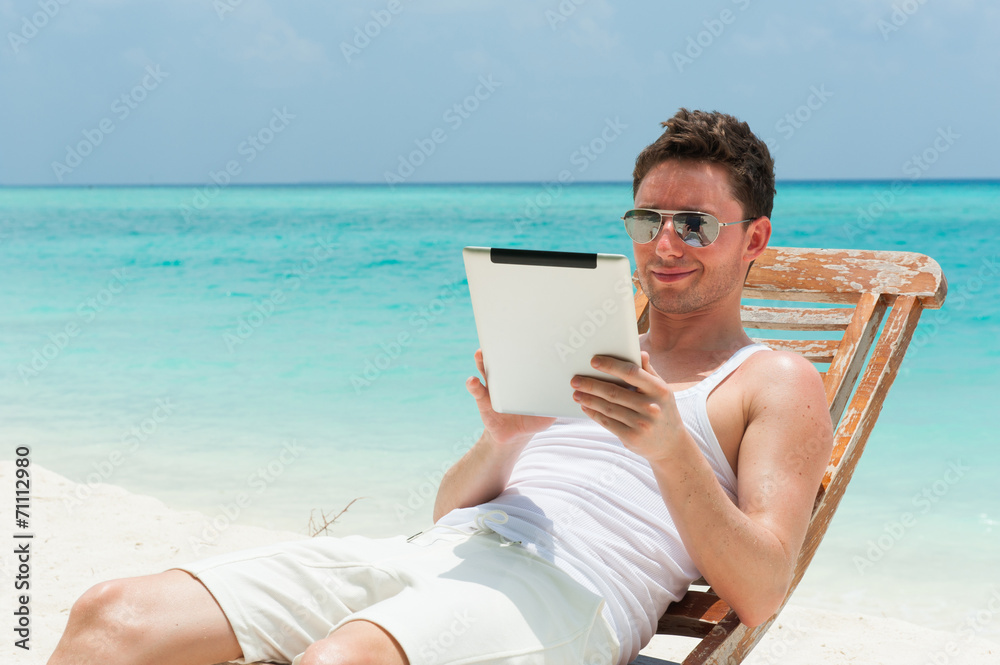 Man sitting with tablet on the beach with the sea, ocean view