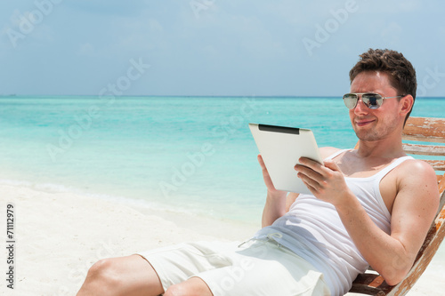 Man sitting with tablet on beach