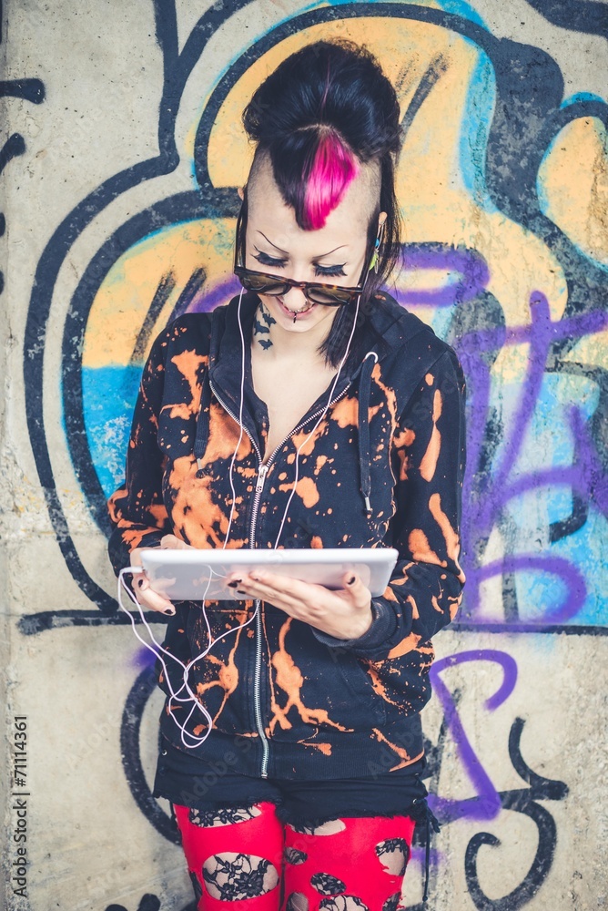 Fototapeta premium Smiling young woman using digital tablet in front of graffiti wall