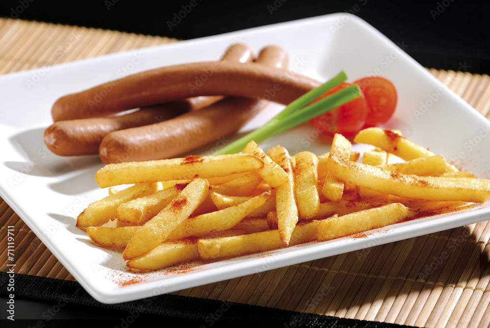 French fries and sausage on white plate.