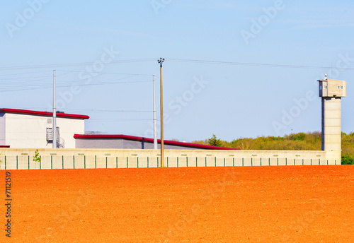 Large prison area with a tall watchtower surrounded photo