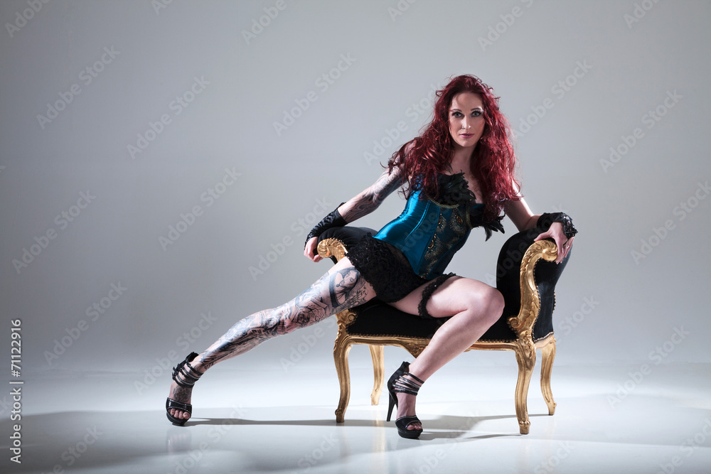Frau mit sexy Tattoo am Bein im Burleque Style auf Barrocksessel Porträt