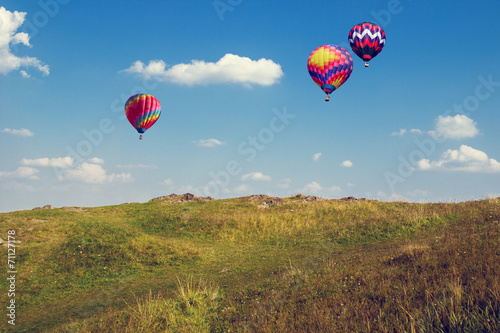 Landscape with three balloons in the blue sky.