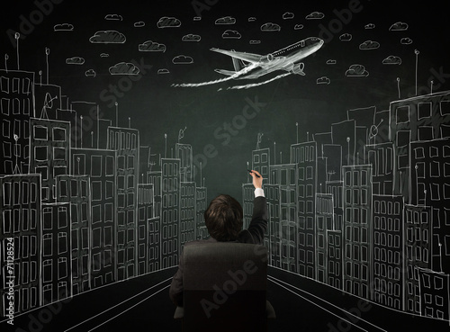 Businessman sitting in front of a cityscape drawing on a chalkbo photo