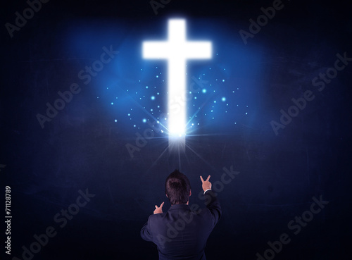 Businessman in front of a glowing cross