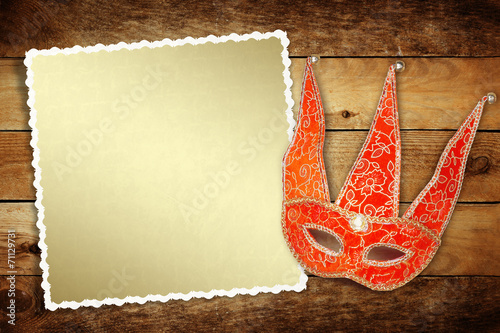 Carnival red mask with old paper for greeting on wooden backgrou