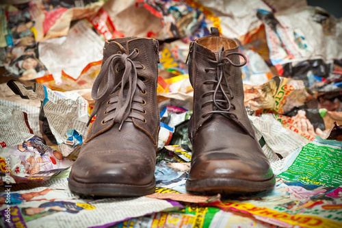 Men's leather boots standing next to crumpled scraps of paper