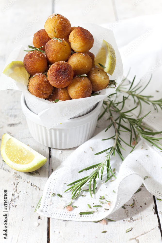 balls of fried potatoes with lemon and rosemary on table balls of fried potatoes with lemon and rosemary on table