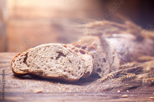 Bread and wheat on wooden table, shallow DOF