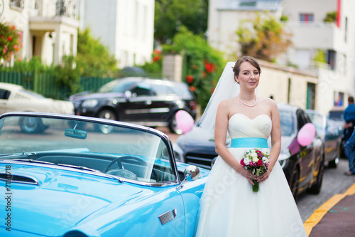Beautiful young bride posing near a blue car © Ekaterina Pokrovsky