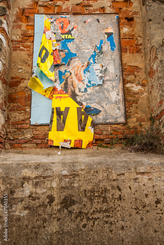 Vecchi poster pubblicitari strappati affissi su muro