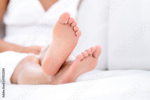 Woman feet closeup - barefoot woman relaxing sofa photo
