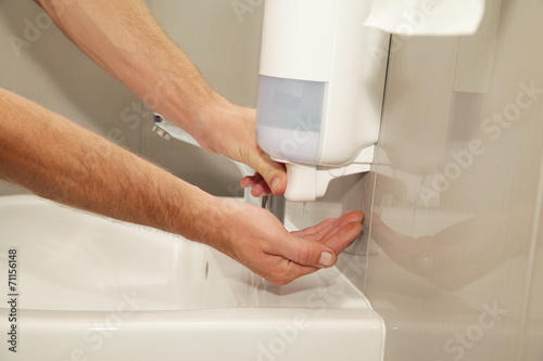 Male hands with soap dispenser use in the restroom