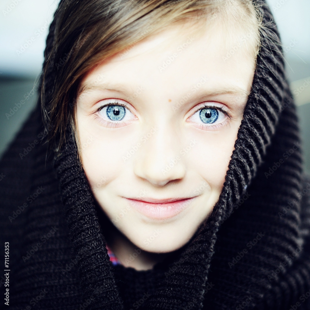 Kid girl in knitted snood on brick wall background Kid girl in knitted snood on brick wall background