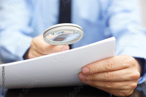 Businessman looking through a magnifying glass to contract photo