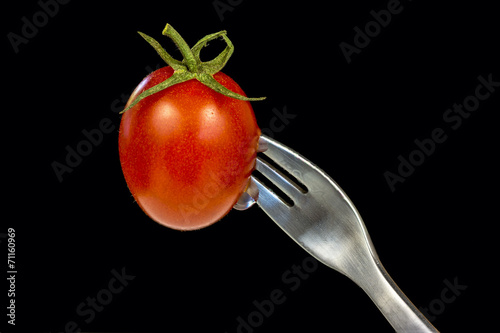 Fresh red ripe tomato stabbed with a fork