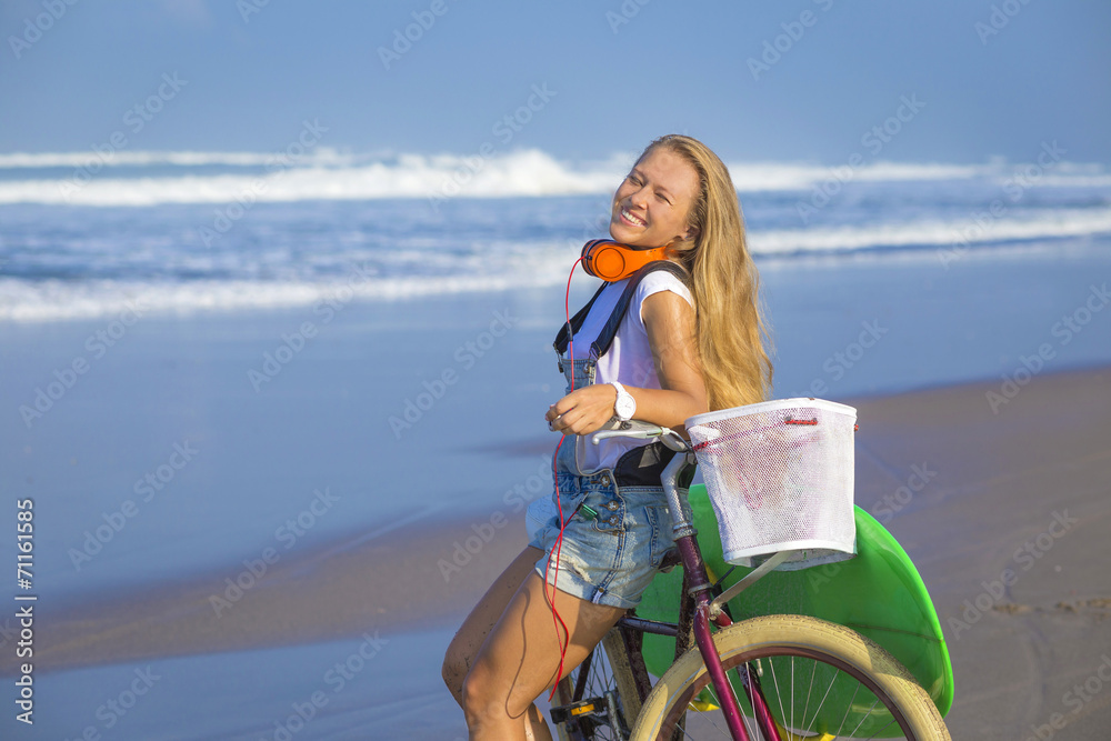 Naklejka premium Young girl with surfboard and bicycle on the beach.