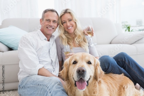 Couple drinking champagne with their dog in front of them