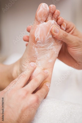 Pedicurist covering customers foot in soap