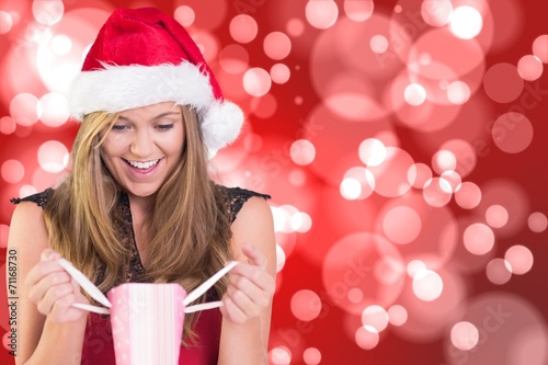 Composite image of festive blonde opening a gift bag