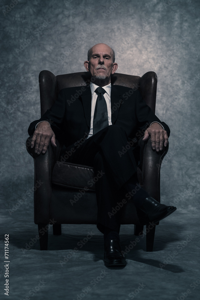 In leather chair sitting senior businessman with gray beard wear
