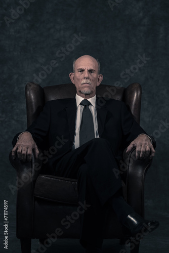 In leather chair sitting senior businessman with gray beard wear