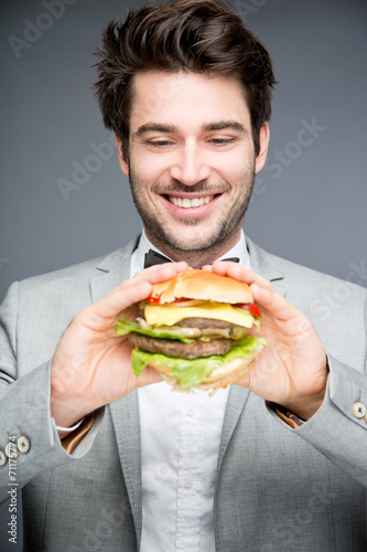 Mann im Anzug mit Burger in der Hand