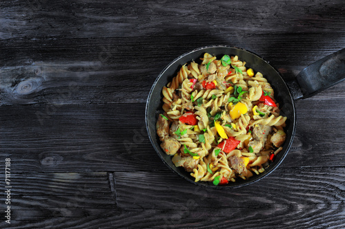 Pasta with meat and vegetables on black saucepan