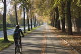 rowerzysta jadący lipową aleją, jesień w parku