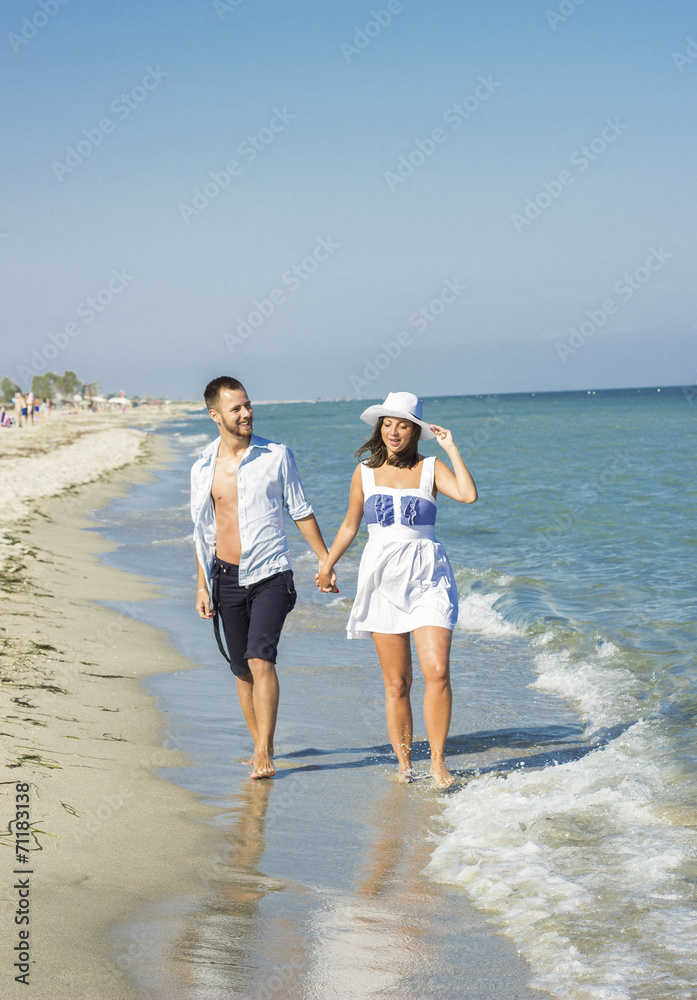 Young happy couple walking on beach holding around each other. Young happy couple walking on beach holding around each other.