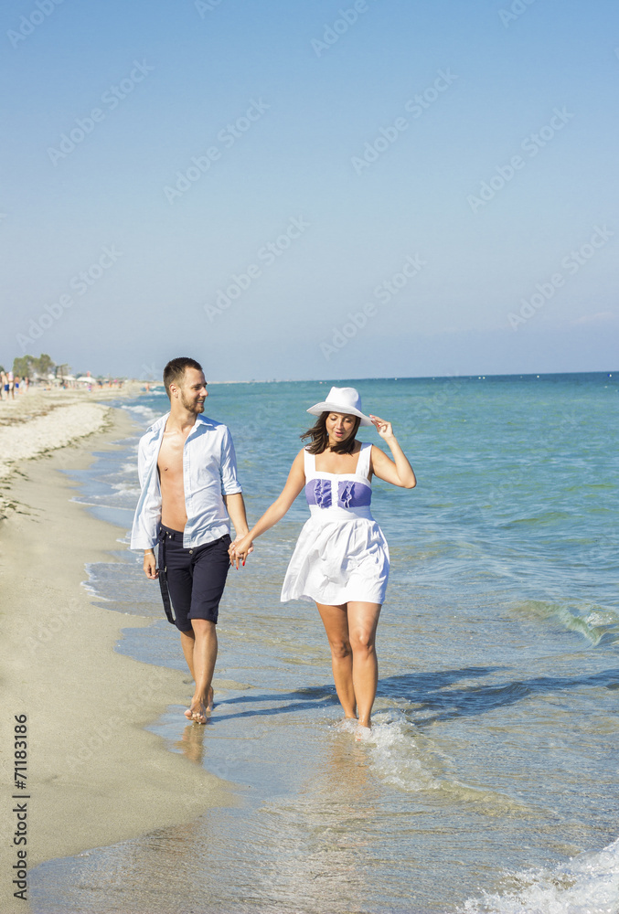 Young happy couple walking on beach holding around each other. Young happy couple walking on beach holding around each other.