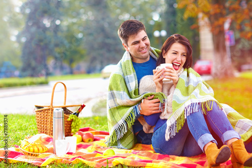 happy couple enjoying autumn picnic in city park