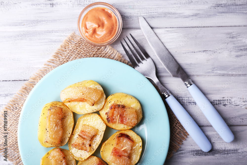 Baked potato with bacon on plate, on wooden background Baked potato with bacon on plate, on wooden background