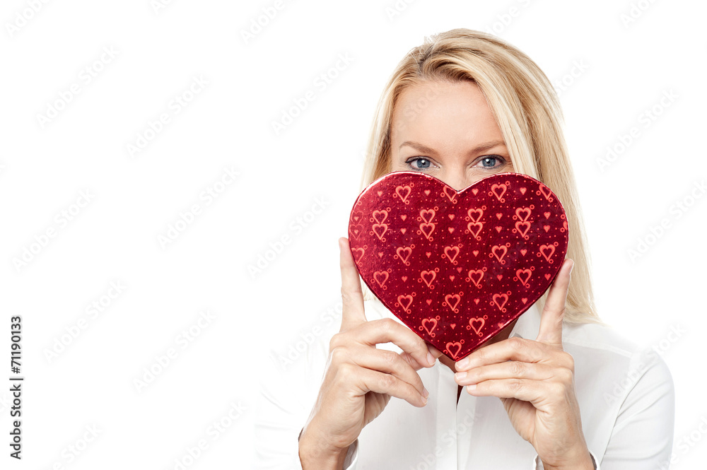 Woman holds a heart shape to her face Woman holds a heart shape to her face